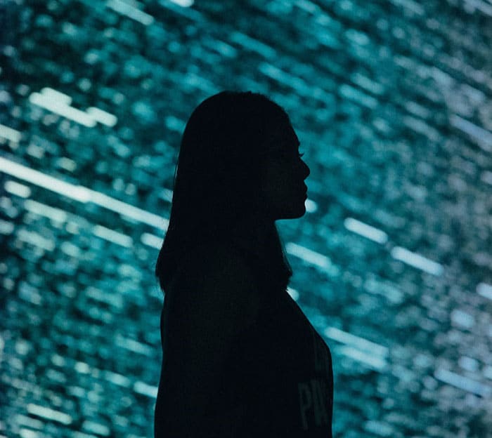 Silhouette of a woman against a dynamic blue and green abstract background, symbolizing modernity and innovation in mortgage lending.