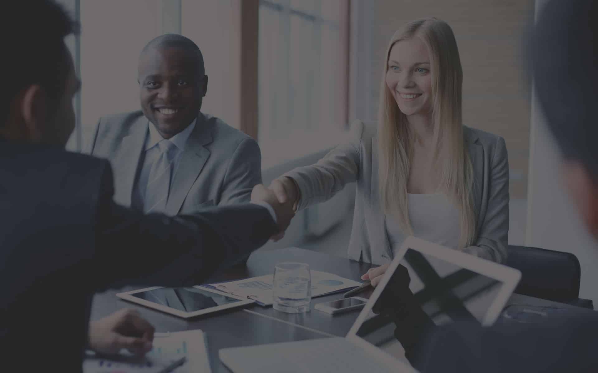 Business professionals shaking hands in a meeting, symbolizing partnership and collaboration in mortgage solutions.