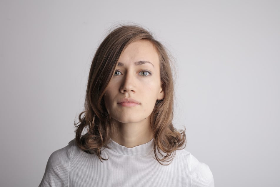 Young woman with shoulder-length hair, wearing a light-colored top, looking directly at the camera against a neutral background, conveying a sense of confidence and readiness, relevant to home buying guidance and financial preparedness.