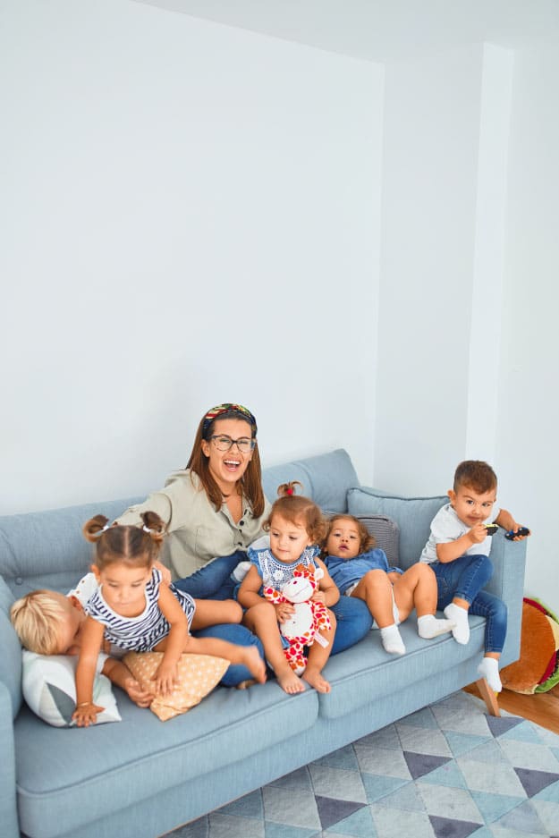 Family enjoying time together on a blue sofa, surrounded by young children, illustrating the warmth and joy of home life relevant to FHA loan benefits for family home buying.