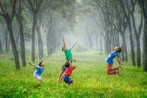 Children playing joyfully in a lush green forest, illustrating the excitement of home and community, relevant to the home buying process.