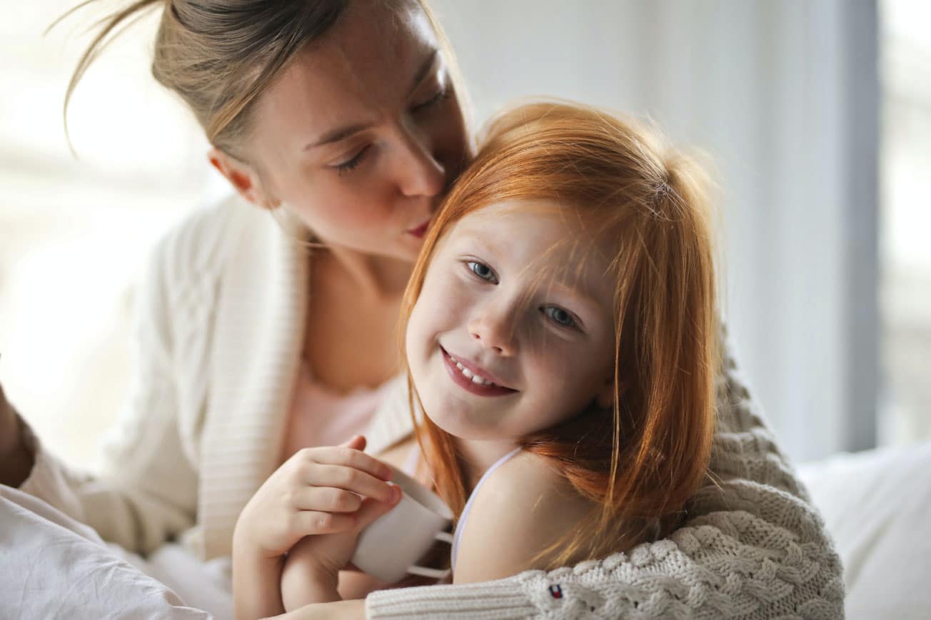Mother and daughter sharing a tender moment, smiling together in a cozy indoor setting, emphasizing family connection and warmth.