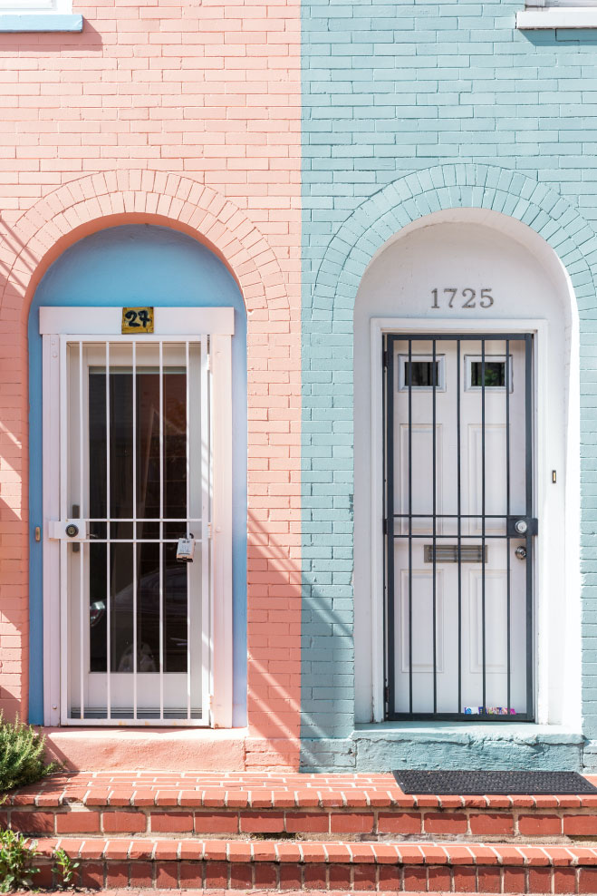 Colorful residential doors in a brick wall, featuring a pink door with security bars and a blue door with a number 1725, highlighting urban home aesthetics and property value considerations.