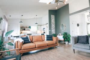 Modern living room with a stylish brown sofa, decorative pillows, and green plants, showcasing a bright and inviting atmosphere ideal for real estate financing discussions.