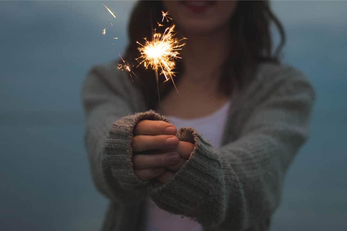 Woman holding a sparkler, symbolizing celebration and teamwork in real estate investment.