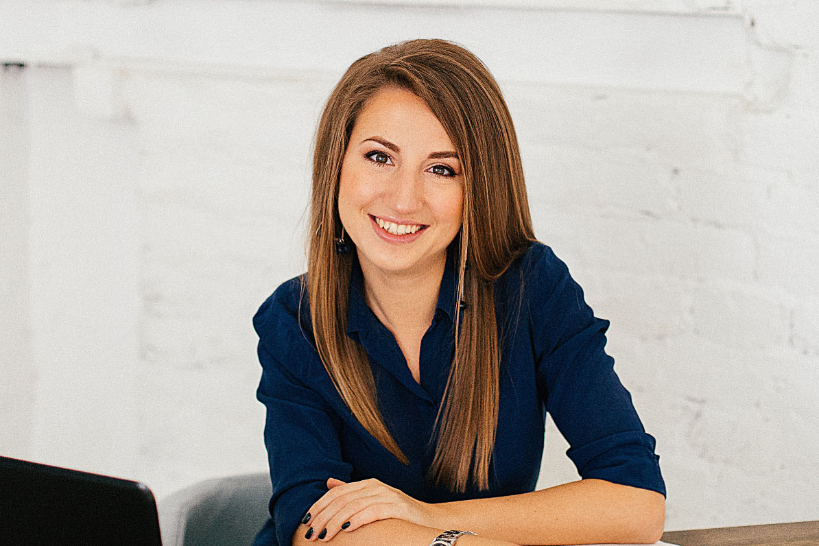 Smiling real estate agent in a blue shirt, seated at a desk, promoting real estate investing strategies and Other People’s Money (OPM) methods.