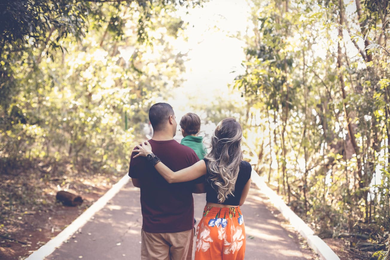 Family walking together on a path in a wooded area, symbolizing home and future planning for potential home buyers.