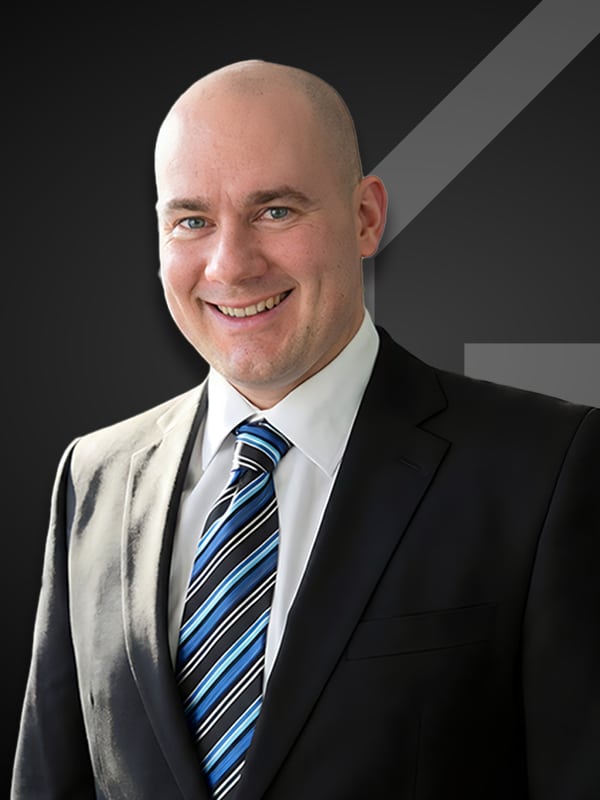 Jacob Timko, professional loan officer at Kash Mortgage Group, smiling in a suit and tie against a dark background.